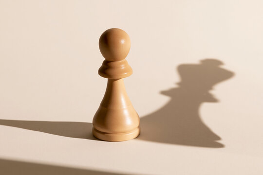 Chess pawn casting a king shaped shadow surreal ambition concept