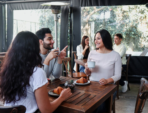 group of latin friends talking and having fun in a coffeeshop in Mexico Latin America, hispanic people holding a coffee cup