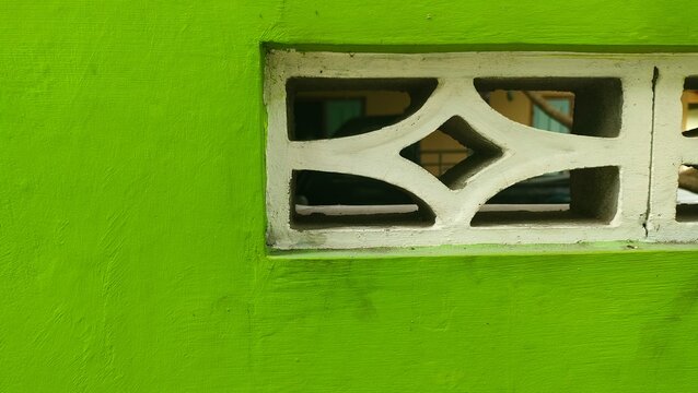 Close-up of a light green painted wall combined with a white concrete ventilation block. Concept of modern architecture, home ventilation, construction materials, and aesthetic background.