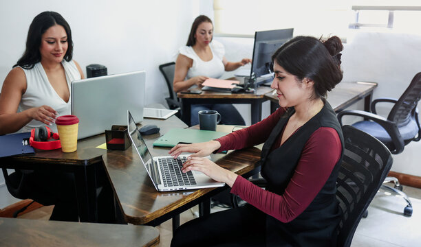group of latina women using laptop at office in Mexico Latin America. Hispanic teamwork of females at workplace 