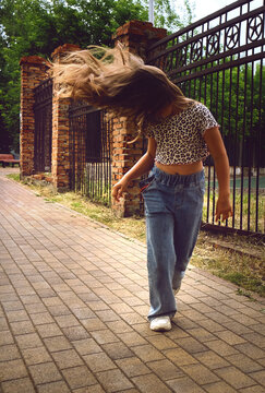 Happy young girl enjoys walking, dancing and jumping freely in the summer sun. Blurred motion captures the energy of the moment, celebrating freedom, carefreeness and individuality.