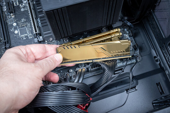 Golden DDR module held in technician's hand symbolizing rising cost of RAM due to AI market demand. Used for high-end gaming or workstation upgrades. Price increase on computer memory
