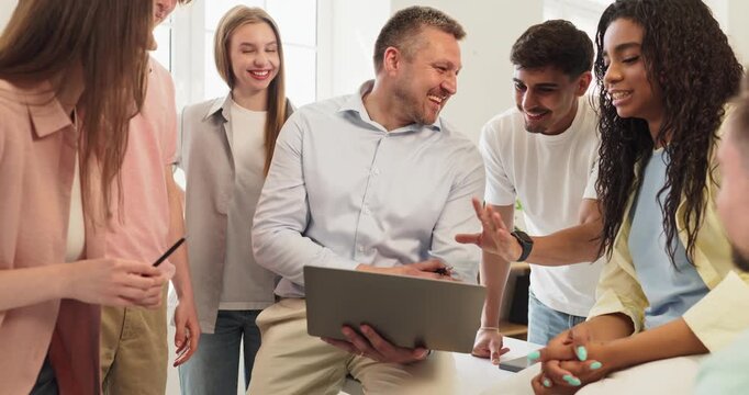 Teacher and students group laptop classroom discussion. Professor leads a lesson as learners collaborate in a bright college stressing applied education. Strong team learning education concept.