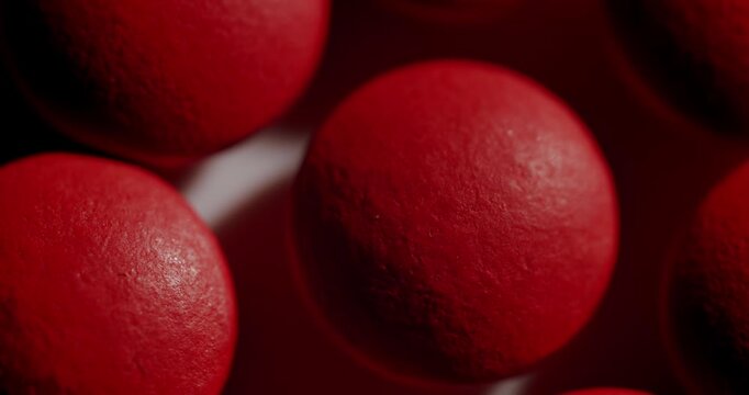 Numerous red round pills arranged in rows on a white surface with moving shadows creating a dynamic texture. Medical concept of pharmaceutical production. Drug manufacturing and healthcare treatment
