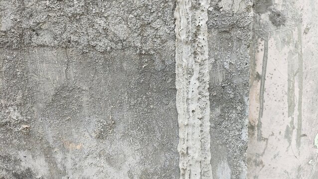 Close-up of a rough concrete and cement wall texture featuring a vertical plaster stripe. Concept of industrial architecture, construction decay, and grunge background design.