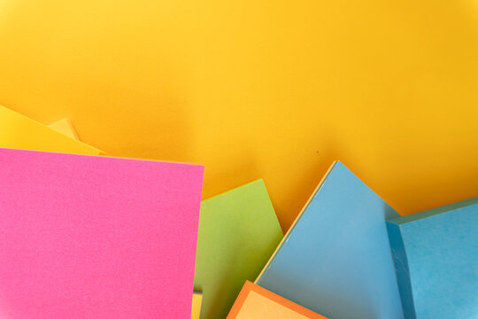 Abstract arrangement of bright paper squares on textured yellow surface