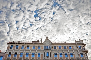 Dramatic mackerel sky with white clouds over historic building facade with reflective blue windows in Saint Petersburg, copyspace architecture scene © seregraff