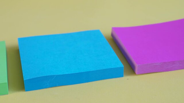 Row of assorted sticky note pads in green, blue, and pink