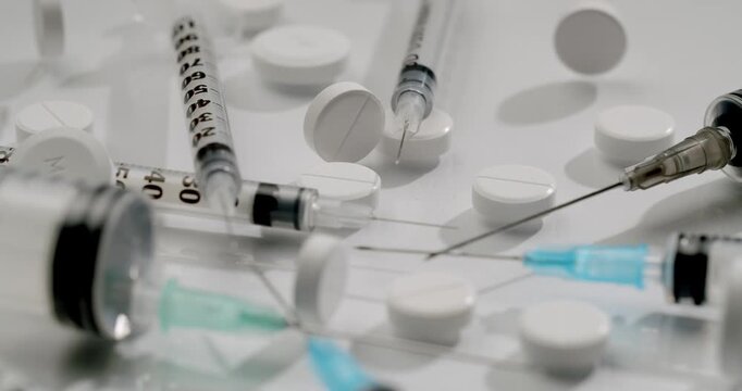 Medical insulin syringes with needles and white pills rotating on a white background, representing concepts like diabetes management, Insulin syringes and pills isolated on a white background.