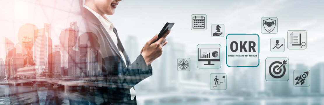 Business Professional Using Smartphone to Manage OKR Goals in a Modern Office Environment with Digital Icons Representing Productivity and Management Tools Fluxor.