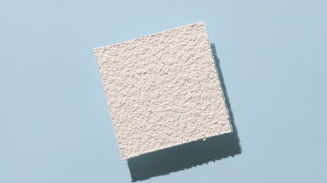 Top view perspective shot of white powder sifted in form of inclined square produces a flowing shadow on a baby blue background | Magnesium stearate commercial concept