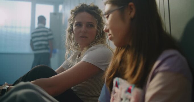 Teacher Sits Beside Withdrawn Teenage Girl on Hallway Floor, Patiently Listening, Creating Safe Space for Honest Conversation. Supportive Relationships That Help Students Navigate Everyday Challenges.