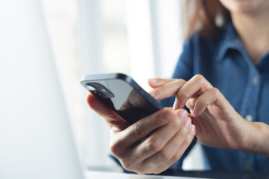 Close up, business woman using smartphone with laptop on desk during working at modern office
