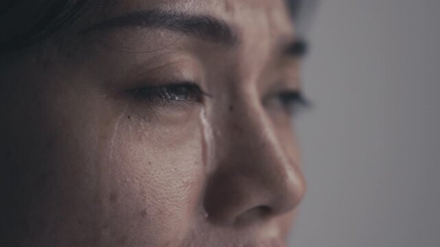 A sad woman crying alone at home, showing emotional pain, depression, fear and stress related to family problems and personal hardship.