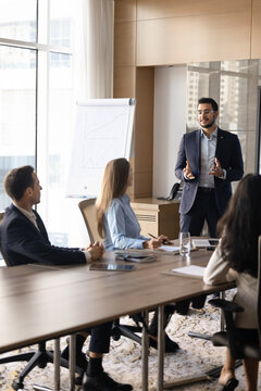 Middle-eastern businessman present business strategy to colleagues at professional meeting, team members engaging in discussion, project development during corporate training, briefing or presentation