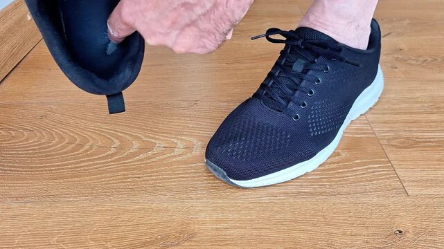 Finger points to a worn sneaker insole, highlighting shoe wear, cushioning, and texture. Indoor footwear detail showing everyday use, comfort, and athletic shoe condition