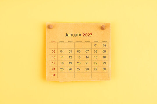 January 2027 brown calendar with wooden thumbtack on yellow background.