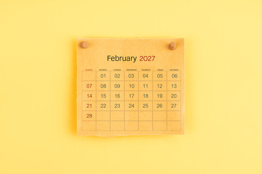 February 2027 brown calendar with wooden thumbtack on yellow background.