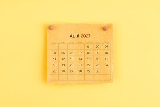 April 2027 brown calendar with wooden thumbtack on yellow background.
