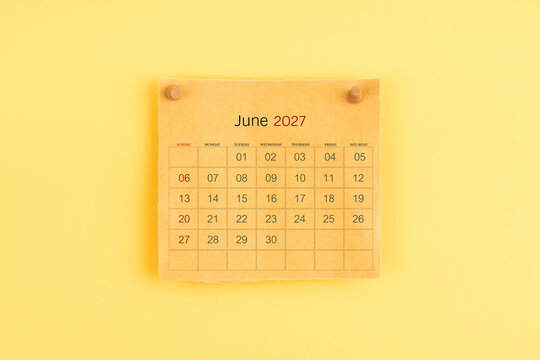 June 2027 brown calendar with wooden thumbtack on yellow background.