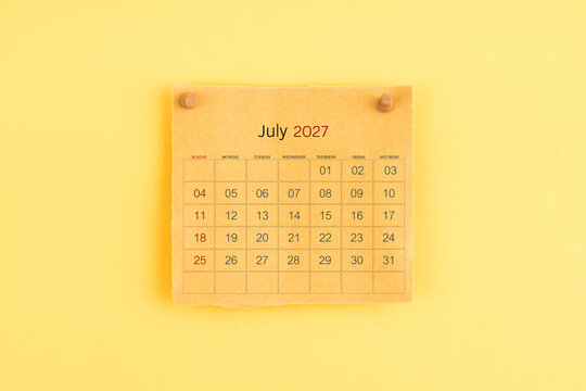 July 2027 brown calendar with wooden thumbtack on yellow background.