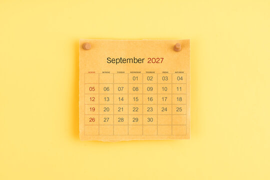 September 2027 brown calendar with wooden thumbtack on yellow background.