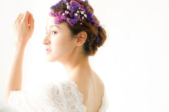 Young woman in white lace dress with purple flower crown in soft bridal portrait