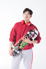 Young man holding skateboard with headphones on white background © HuaThuy