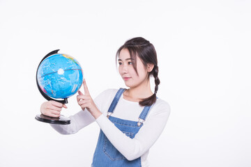 Fototapeta premium Young woman studying a globe on a white background