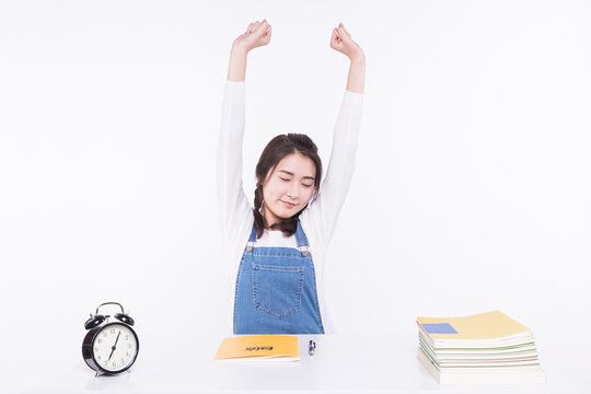 Young woman stretching after waking up beside alarm clock and study materials