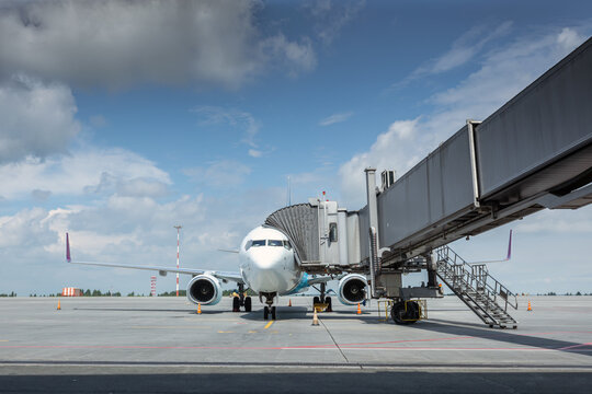 Front view of the passenger airplane at the boarding bridge on the airport
