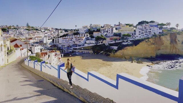 Woman Walking Down Path Overlooking Coastal Town and Beach, Portugal Algarve Travel Concept, Carvoeiro
