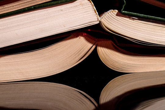 Binding of stacked books on a reflective surface, close-up