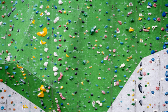 Eine riesige Kletterwand mit bunten Griffen und Tritten in einer Kletterhalle. Die moderne Sportanlage bietet ideale Bedingungen f&uuml;r ein herausforderndes Kraft- und Ausdauertraining.