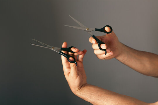 Male hands with hairdresser scissors on grey background, closeup