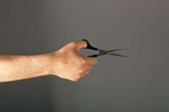 Male hands with hairdresser scissors on grey background, closeup