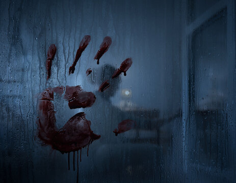 Bloody handprint on a window pane &mdash; a background concept for scary horror or a crime scene.