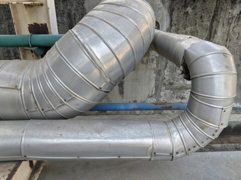 Damaged thermal insulation jacket on industrial steam pipelines outside factory wall
