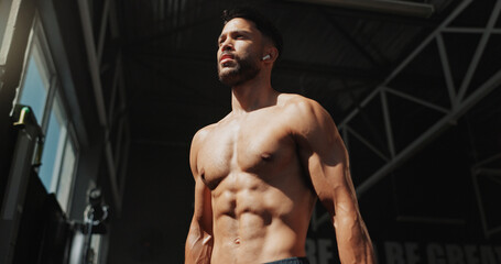 Naklejka premium Fitness, gym and bodybuilder man with music and thinking of training, muscle growth and self care. Earphones, workout playlist and person or health club membership for exercise, strong and wellness