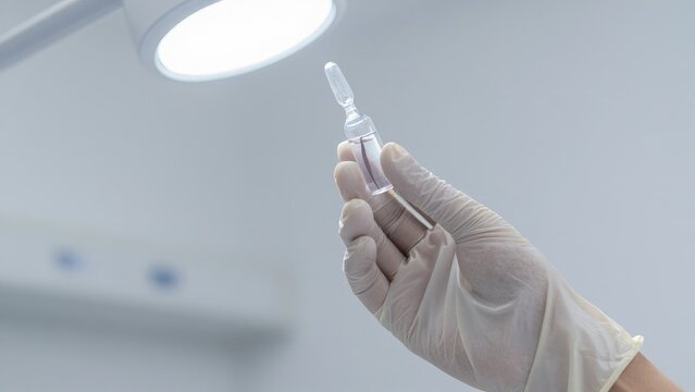 Hand Holding Glass Ampoule Under Medical Examination Light