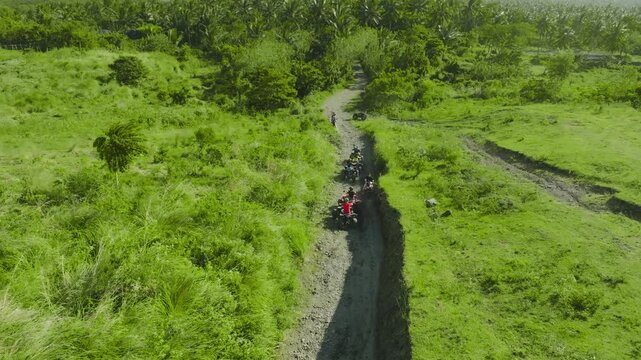 4K Drone Aerial View of Tourists Riding ATVs Near Mayon Volcano Philippines. exciting off-road adventures, lush green countryside, and tropical coconut palm groves