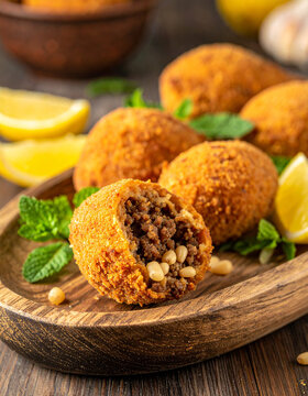 Oval shaped fried kibbeh shells stuffed with minced meat and pine nuts are served with fresh lemon and mint.