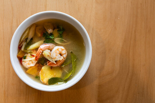 Overhead view on delicious clear soup Thai Tom Yum with prawns, also called Nam Sai in Thai served in bowl in restaurant.