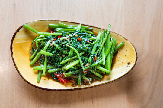 Simple yet delicious Thai style pan fry morning glory with chili pepper served on plate