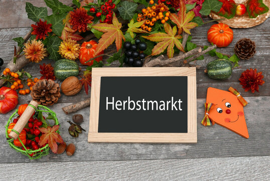 Kreidetafel mit Aufschrift Herbstmarkt umgeben von herbstlicher Dekoration.