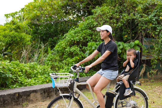 Woman riding bicycle with young child in seat