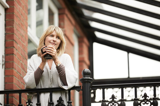 Thinking, coffee or woman on balcony with nostalgia, daydreaming or memory in calm mindset. Inspiration, reflection or mature person in home with drink, flashback or insight in peaceful perspective.