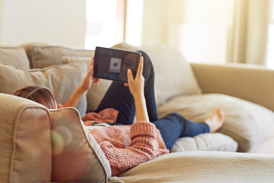Woman, tablet screen and relax on sofa for social media, streaming movie and scroll in living room. Female person, website and subscription on couch for online, search or reading ebook in apartment