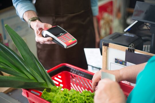 Customer paying with contactless card reader at a grocery store checkout counter checkout terminal customer