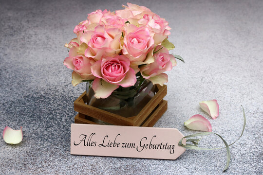 Romantischer Geburtstagsgru&szlig;: Rosa Rosenstrau&szlig; in einer Vase mit Beschriftung Alles Liebe zum Geburtstag auf einem Holzschild.